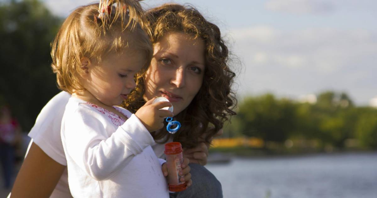 Vrouw staat buiten met kind in armen